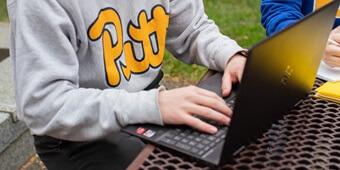 Student in gray sweatshirt on laptop
